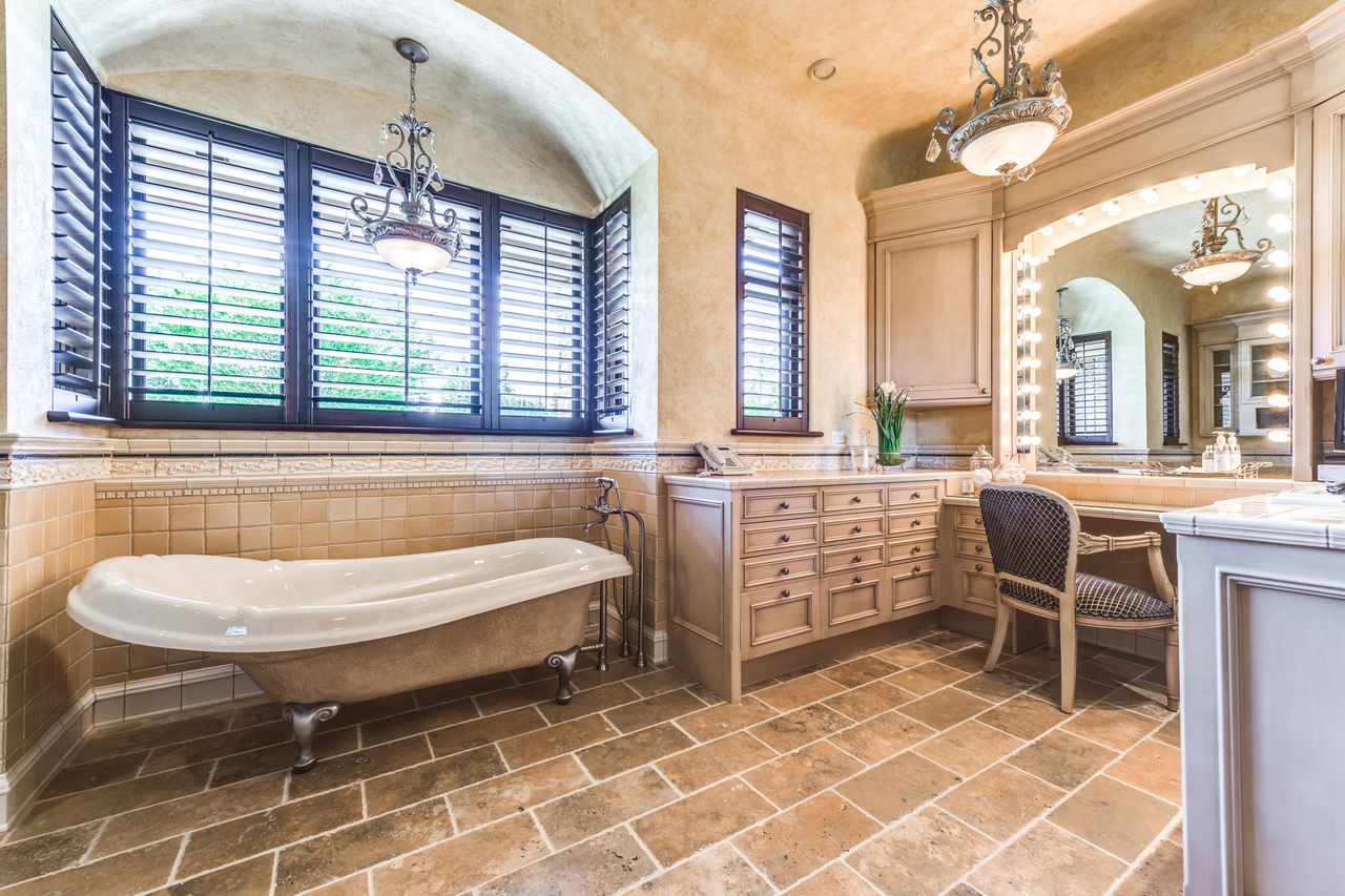 Elegant bathroom in Vancouver featuring a freestanding tub, makeup vanity, large mirror, and warm tile flooring—a stunning example of refined construction in British Columbia.
