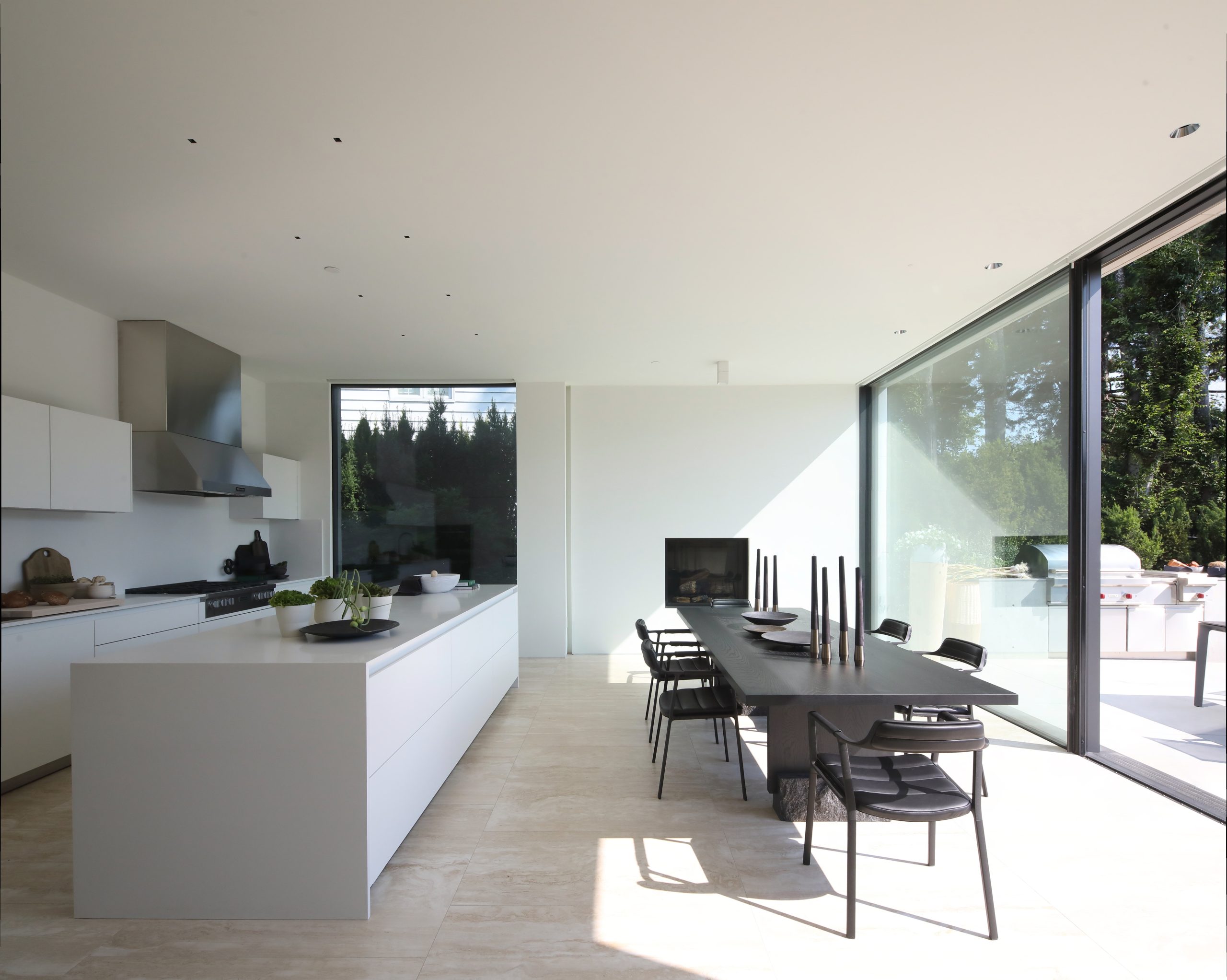 Kitchen and dining area with large windows, black chairs, and views of trees outside—showcasing the quality found in custom homes throughout British Columbia.