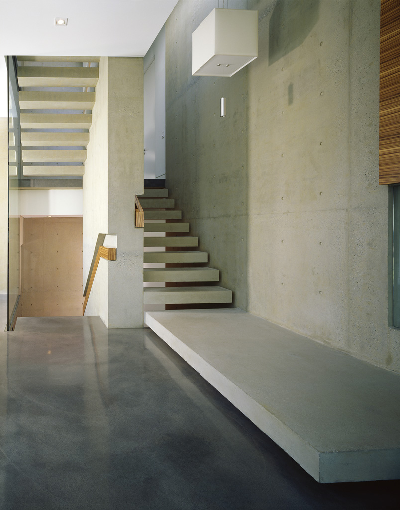 Interior with concrete walls, floating staircase, and polished concrete floors in minimalist design by a Vancouver general contractor.